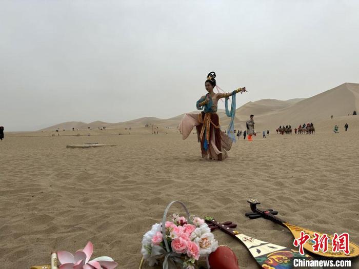 圖為2023年4月底，敦煌大漠“逐舞者”奧楠在鳴沙山月牙泉景區(qū)視頻直播敦煌舞?！●T志軍 攝