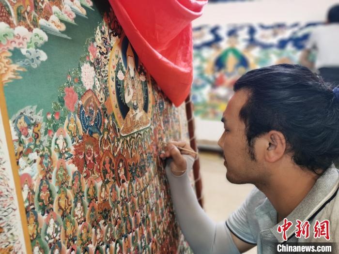 圖為更登才讓的徒弟繪畫唐卡?！?zhí)砀?攝
