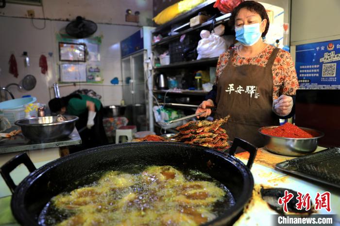 圖為平安驛·河湟民俗文化體驗(yàn)地內(nèi)的商戶炸干板魚。　薛蒂 攝